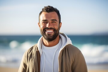 Portrait of smiling young man standing on beach in front of ocean