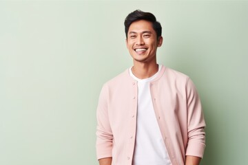 Portrait of a handsome young asian man smiling against green background
