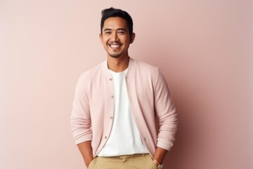 Fototapeta premium Handsome young Asian man smiling and looking at camera while standing against pink background