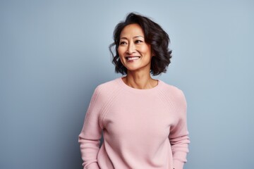 Obraz premium Portrait of a smiling middle-aged woman standing against blue background