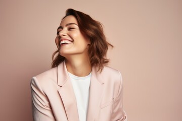 Fototapeta premium Portrait of a smiling young woman in a pink jacket on a beige background