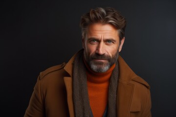 Fototapeta premium Portrait of a handsome middle-aged man in coat and scarf on black background