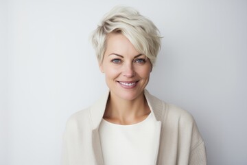 Portrait of smiling mature businesswoman standing against white background in office