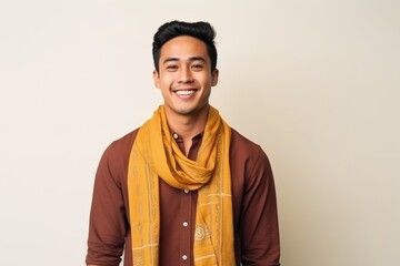 Fototapeta premium Young handsome Indian man with yellow scarf smiling and looking to the side