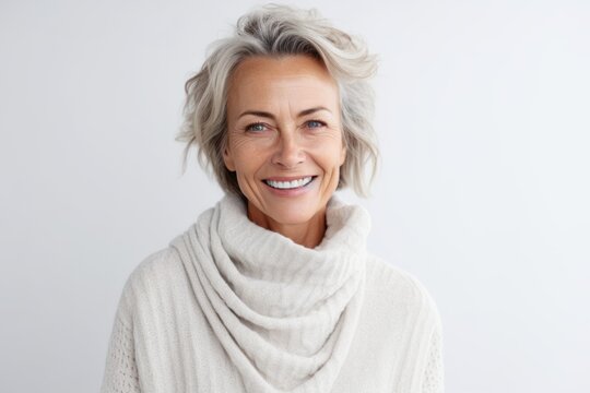 Portrait of happy mature woman with grey hair wearing warm sweater and smiling at camera