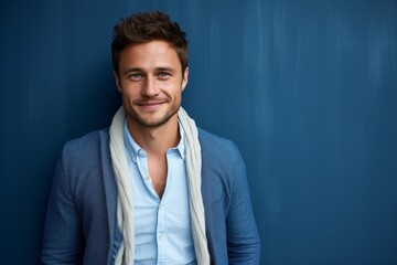 Fototapeta premium Portrait of a handsome young man smiling against blue wall background.