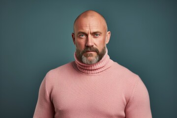 Portrait of a bald man in a pink sweater on a blue background