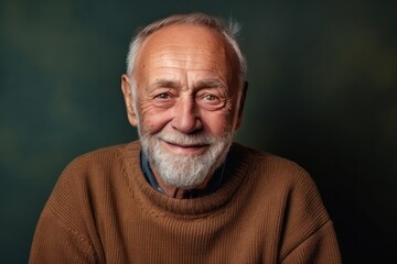 Obraz premium Portrait of a smiling senior man in a brown sweater on a dark background