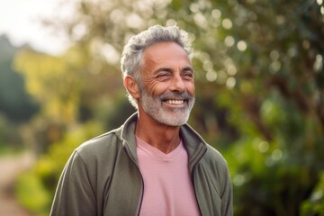 Portrait of happy senior man smiling at camera while standing in park