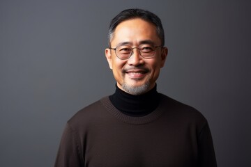 Fototapeta premium Portrait of a happy asian man wearing glasses against grey background