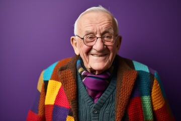 Portrait of an elderly man in a bright sweater on a purple background