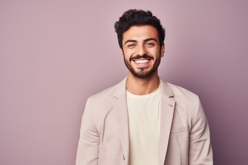 Fototapeta premium Handsome young man looking at camera and smiling while standing against purple background