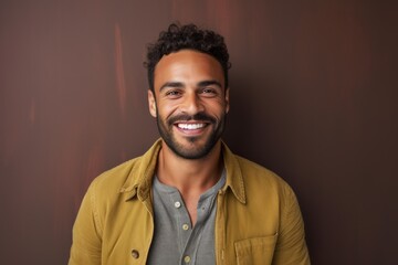Obraz premium Portrait of a handsome young man smiling against a brown background.