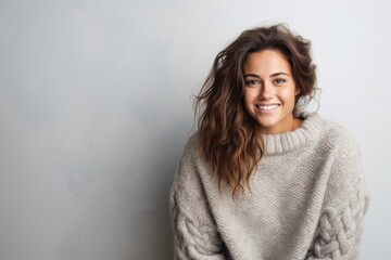 Fototapeta premium Portrait of a beautiful young woman in a sweater on a gray background