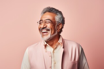 Obraz premium Portrait of a happy Indian senior man wearing glasses and smiling at camera against pink background