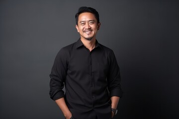 Fototapeta premium Portrait of happy young Asian man smiling at camera against black background