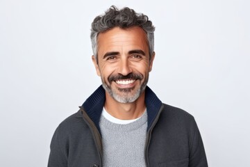 Obraz premium Portrait of handsome mature man looking at camera and smiling while standing against grey background