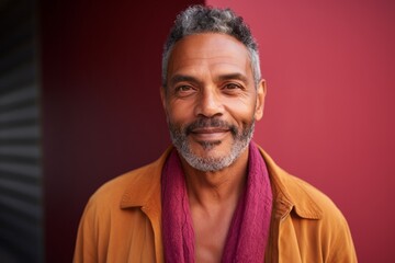Obraz premium Portrait of a smiling Indian man with a red scarf against a red background