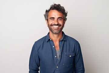 Fototapeta premium Portrait of a handsome Indian man smiling at the camera while standing against white background