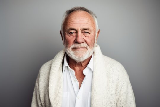 Portrait of a senior man with a white beard in a white sweater.