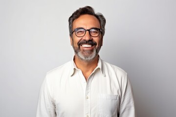Obraz premium Portrait of a happy mature Indian man with eyeglasses on grey background