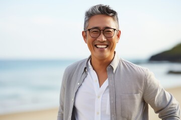 Portrait of a smiling asian man wearing glasses on the beach