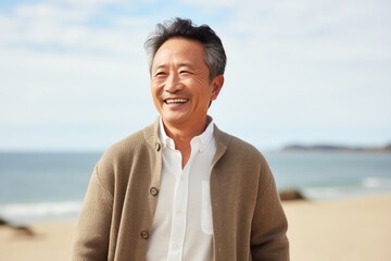 Portrait of happy senior man standing on the beach, looking at camera