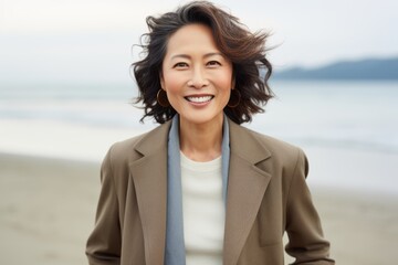 Portrait of happy mature Asian woman on beach, looking at camera