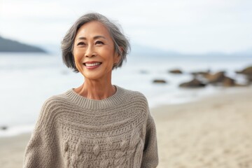Portrait of a happy senior woman smiling at the camera while standing on the beach