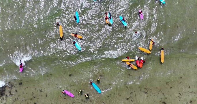 An overhead view of colourful surfboards, surfers gathered to ride 4k