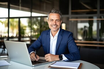 Fototapeta premium Smiling mature adult business man executive sitting at desk using laptop. Happy busy professional mid aged businessman ceo manager working on computer corporate technology in office