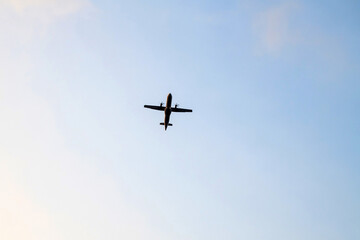 Propeller airplane is flying against isolated blue sky at evening.