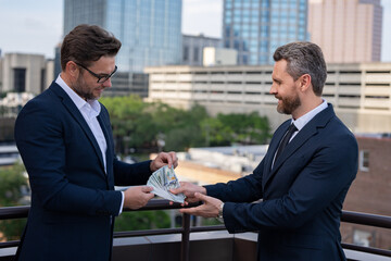 Fototapeta premium Illegal corruption, bribery concept. Two business team men. Businessmen giving money. Business man offering money for collage. Offering money for business.