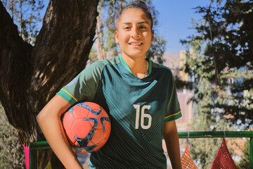 latina woman with soccer ball and green t-shirt smiling in a park in bolivia latin america