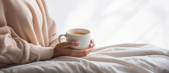 Fototapeta na wymiar Young woman hand holding white cup of coffee on the bed in the morning.Generative ai