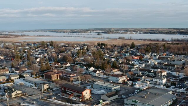 Slow aerial dolly left shot of snow covered town of Thurso Quebec Canada with the frozen Ottawa River visible in background on a winter day.