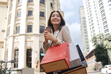 Cheerful Asian woman holding shopping bags.Beautiful Asian woman in casual style shopping in the city.