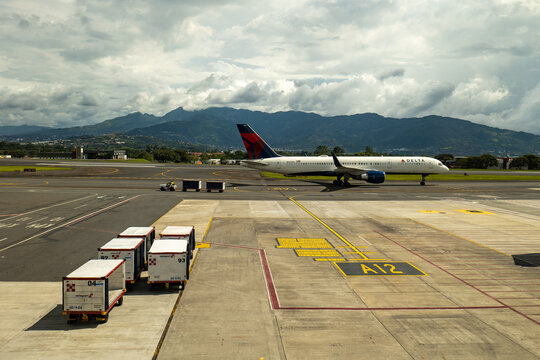 San Jos&eacute;, San Jos&eacute; Province, Costa Rica - 23 October 2022: Delta Air Lines Airplane, Trolley Cars and Containers on the Tarmac at San Jose International Airport (SJO)