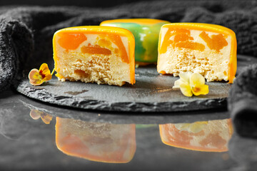 Gourmet Entremet with layered sponge cake, mango jelly and mousse, covered in a mirror tropical coloured mirror glaze.