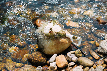 A bouquet of white roses laying on the rocks at the stream.