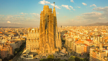 Aerial sunrise image of the Sagrada Familia cathedral in Barcelona, Spain. The cathedral is bathed...