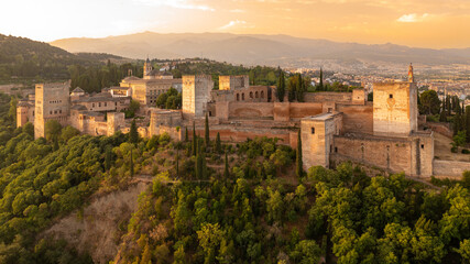The Alhambra fortress in Granada, Spain at sunrise. Fortress is bathed in golden-reddish light. - obrazy, fototapety, plakaty