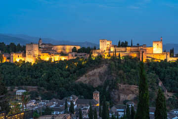 The Alhambra fortress in Granada Spain during the blue hour. Fortress is bathed in golden light,...