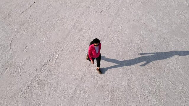 Aerial shot of an Asian woman hiking across the Bonneville Salt Flats flats in Utah