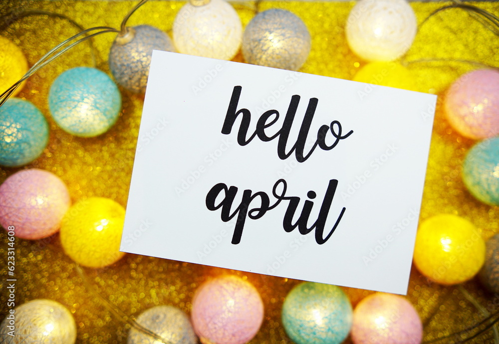Poster hello april text on paper card top view on yellow bokeh background