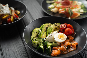 Balanced diet, cooking, culinary and food concept. Ketogenic diet breakfast. Salt salmon salad with avocado, sesame, tomato, cucumber and quail egg