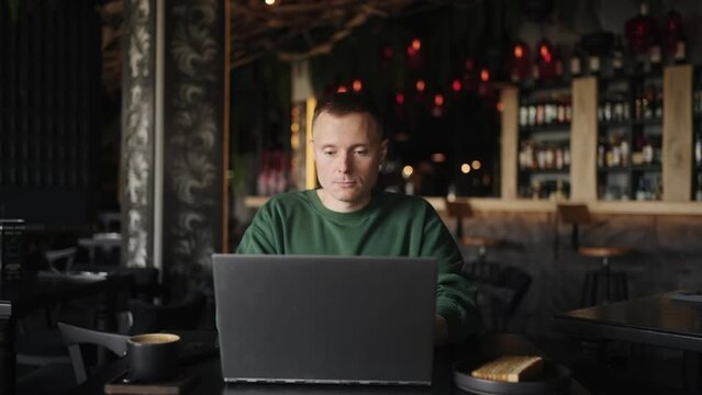 Businessman Working Remotely With Laptop In Cafe, Frontal Portrait, Dolly Shot Moving Back