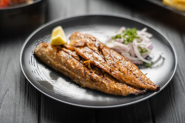 Baked mackerel fish in plate with lemon and onion, menu recipe, top view