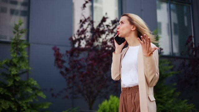 Determined assertive young businesswoman engaged in a passionate conversation on mobile phone outdoors. Unsatisfied female customer passionately expressing dissatisfaction and frustration subordinate.