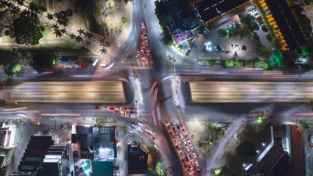 Aerial hyperlapse time-lapse drone view fly up of traffic cars transportation, intersection in city at night, fast car lights.